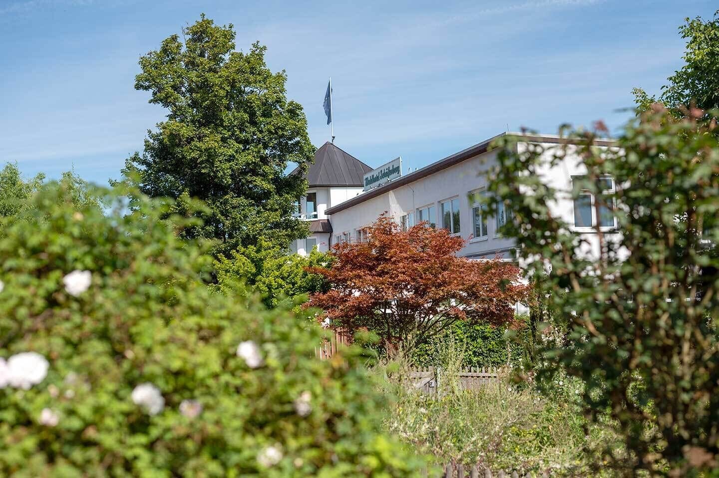 Un edificio rodeado de follaje y árboles, con una bandera.