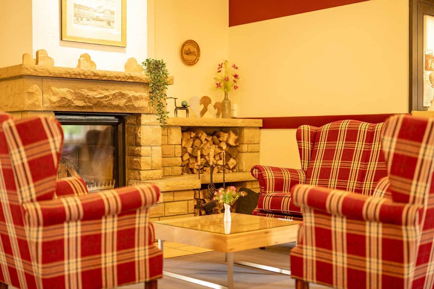 A cozy room with a fireplace, plaid chairs, and a coffee table.