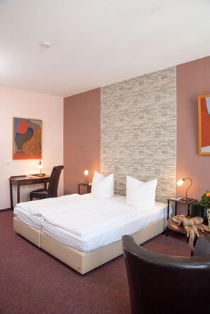 A hotel room with a bed, desk, chair, and a wall with a textured pattern. - Hotel Adagio (Leipzig)
