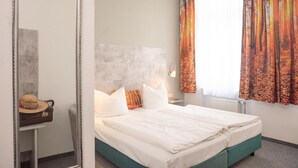 A hotel room with a bed, a nightstand, a lamp, a suitcase, and a hat. - Hotel Adagio (Leipzig)