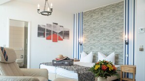 A hotel room with a bed, a chair, a suitcase, a vase with flowers, and a wall with striped wallpaper. - Hotel Adagio (Leipzig)