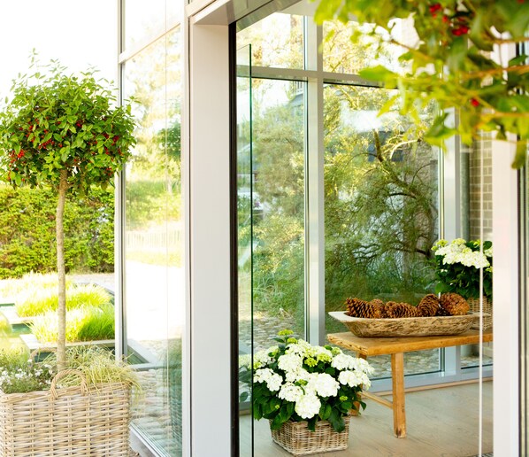 Un interior moderno con ventanas amplias, una mesa de madera con cestas y plantas en macetas.