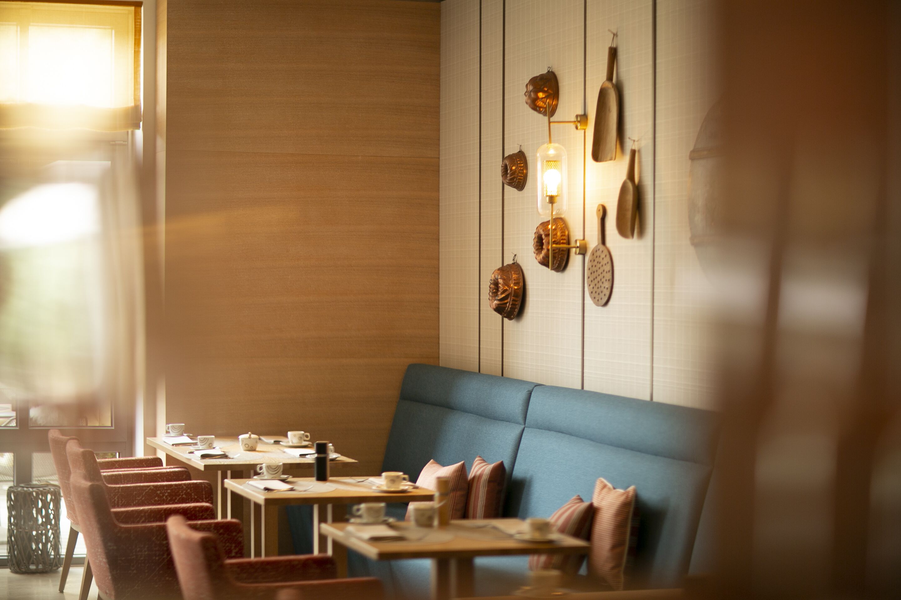 A restaurant with a blue booth seating area, wooden tables, and a wall decorated with various items.