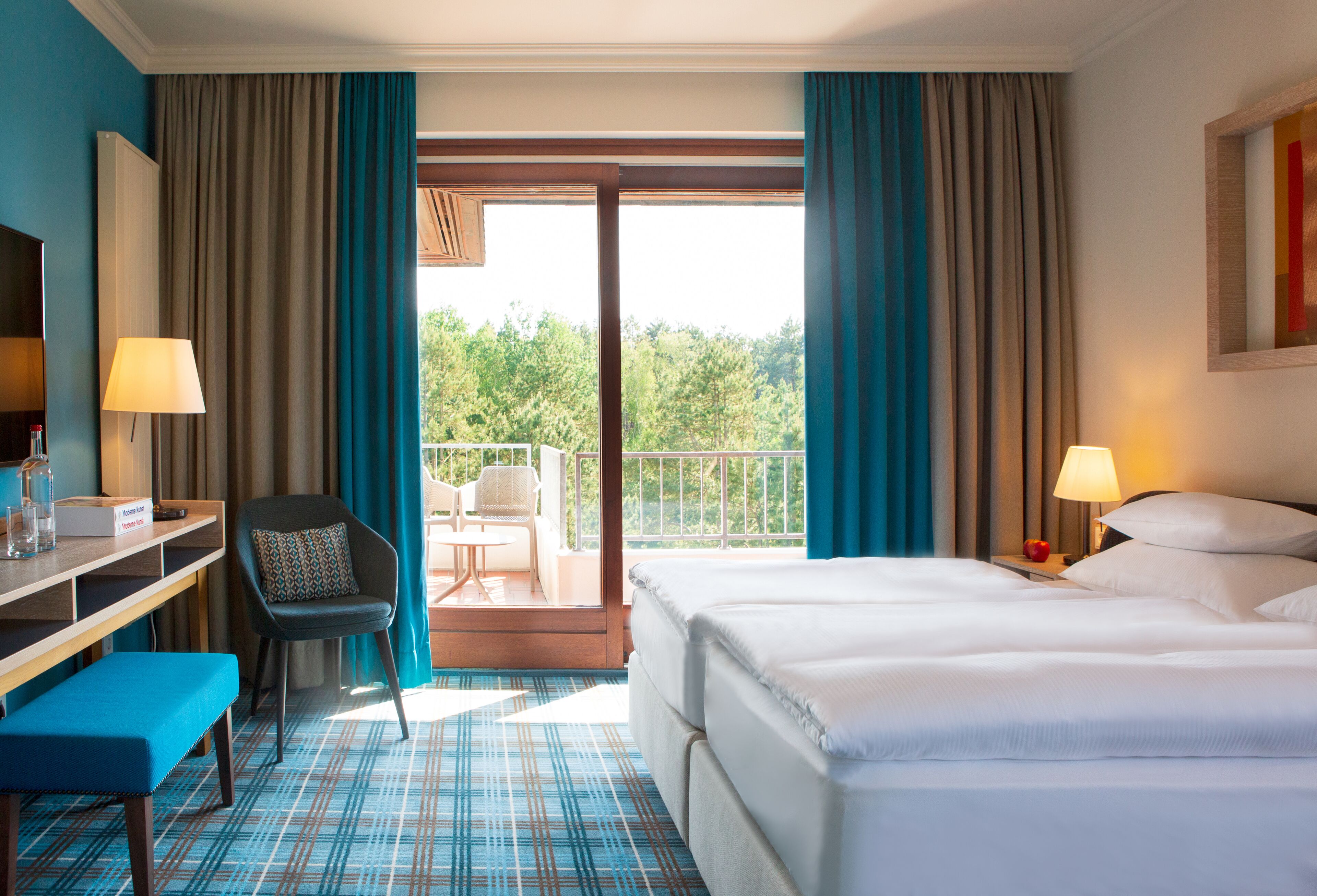 Une chambre d’hôtel avec un lit, un bureau doté d’une lampe, une chaise et une vue sur l’extérieur.