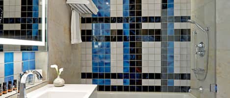 Un baño moderno con un lavamanos blanco, cabina de ducha con mampara de vidrio y salpicadero de azulejos.