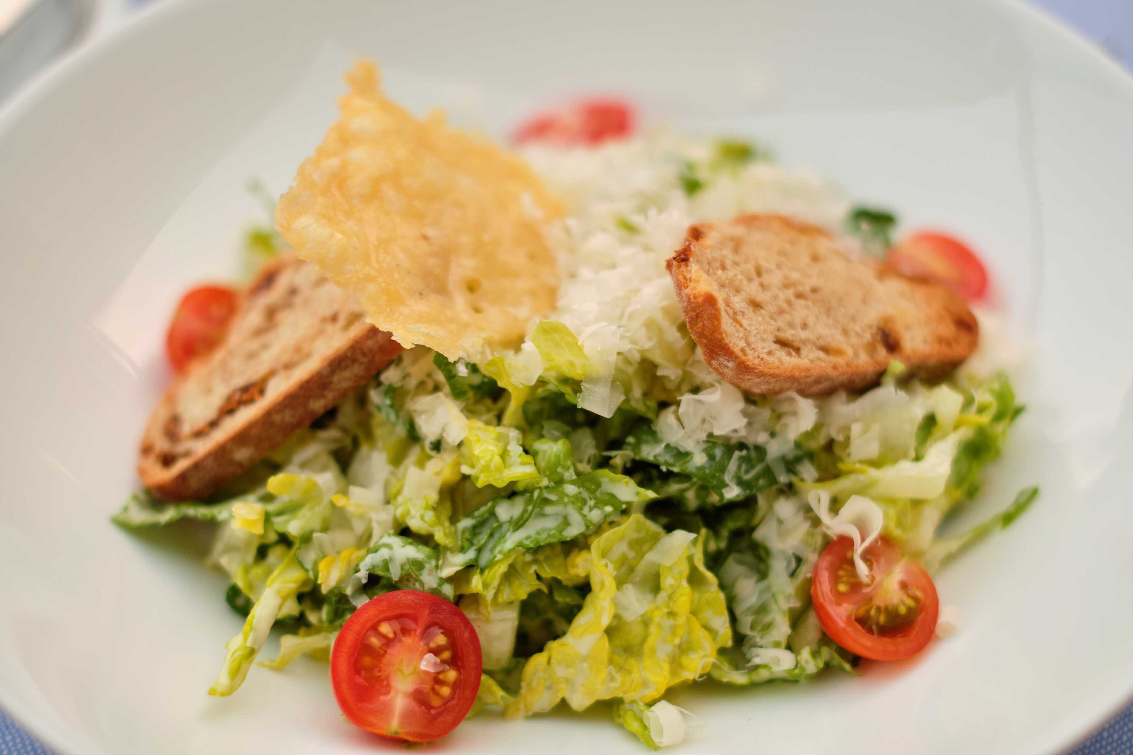 A plate of salad with lettuce, tomatoes, and croutons.