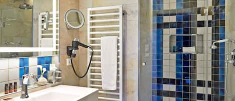 A modern bathroom with a large mirror, a sink, a toilet, and a glass-enclosed shower.