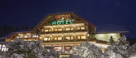A hotel with a prominent "HOTEL" sign, multiple balconies, and snow-covered trees in the foreground.