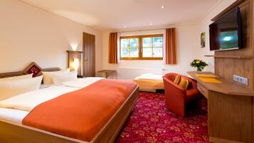 Een hotelkamer met een bed, een bureau, een stoel, een televisie en een raam met gordijnen.