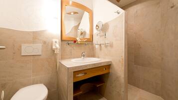 Une salle de bain comprenant des toilettes, un lavabo, un miroir et une douche.