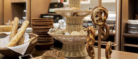 Una mesa de buffet con diversos panes, pasteles y pretzels.