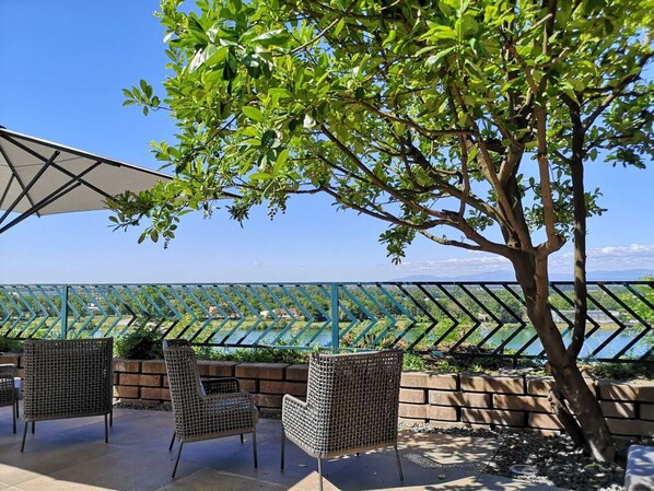 An outdoor seating area with wicker chairs and a view of a lake and mountains. - Hotel Stadt Breisach (Breisach)