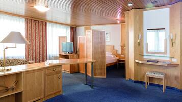 Ein Hotelzimmer mit einem Holztisch, einem Fernseher, einem Bett und einer kleinen Sitzecke.