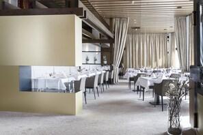 A modern restaurant with a long dining area, white tables, and chairs. - Hotel Stadt Breisach (Breisach)