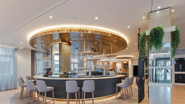 A modern bar area with a curved counter, bar stools, and a glass partition. - SEETELHOTEL Ostseehotel Ahlbeck (Heringsdorf)
