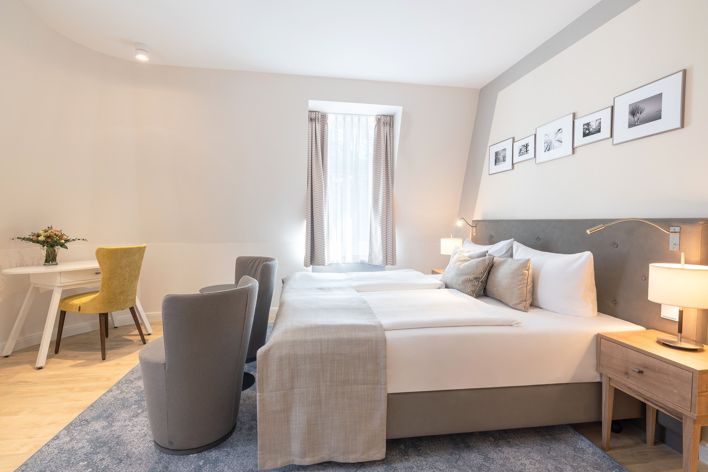 Hotelkamer met een groot bed, een bureau, een stoel en een nachtkastje met een lamp.