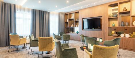Een moderne hotelkamer met een grote flatscreen-tv, comfortabele zitplaatsen en ingebouwde planken met decoratieve objecten.