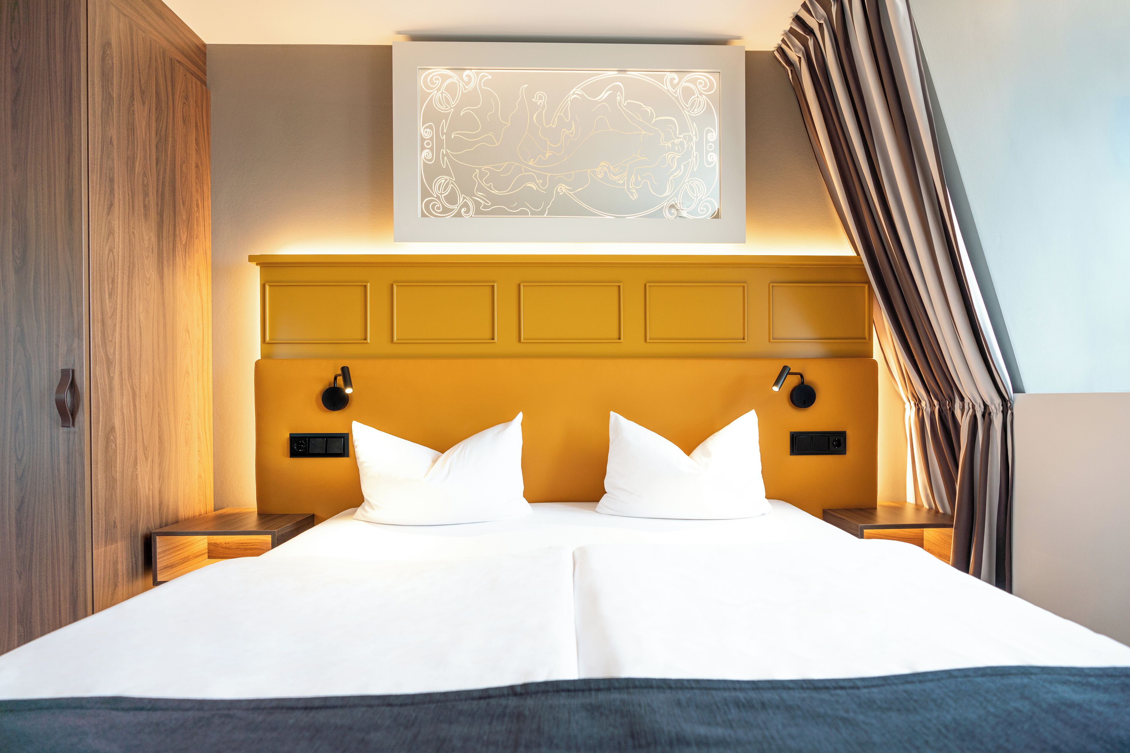 A double bed with a wooden headboard, two bedside tables, and a wall-mounted light fixture.