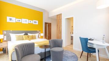Ein Hotelzimmer mit einem Bett, zwei Sesseln, einem Schreibtisch und einem kleinen Tisch.