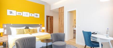 A hotel room with a bed, two armchairs, a desk, and a small table.
