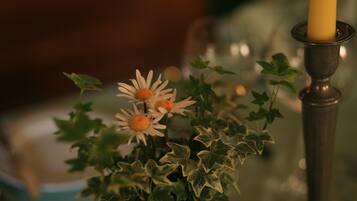A candle in a holder, surrounded by ivy and flowers.