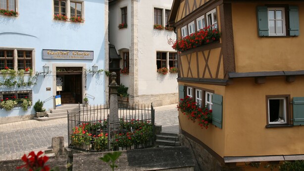 Una calle tradicional europea con un edificio que dice "Gasthof Glocke".