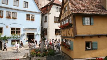 A historic street with traditional European architecture, including half-timbered houses and a sign for "Gasthof Glocke."