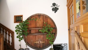 Una pared de barriles de madera con plantas en macetas, una pequeña ventana y una vid decorativa.