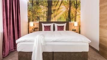 Ein Hotelzimmer mit einem grossen Bett, zwei Nachttischlampen, einem Kopfteil mit einem Waldgemälde und einer Holztür.