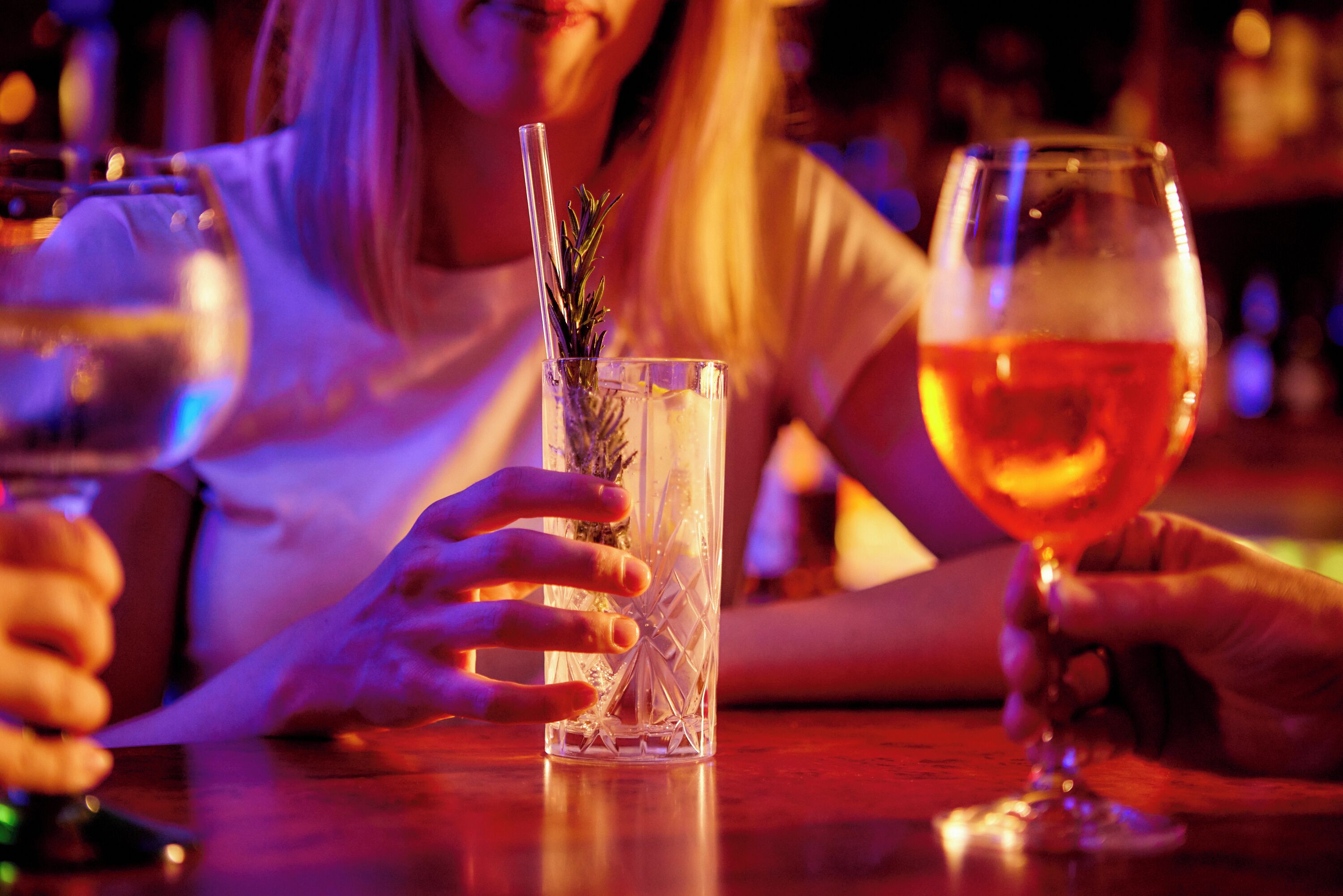Een barsetting met een helder glas gevuld met een drankje en een rozemarijn takje.
