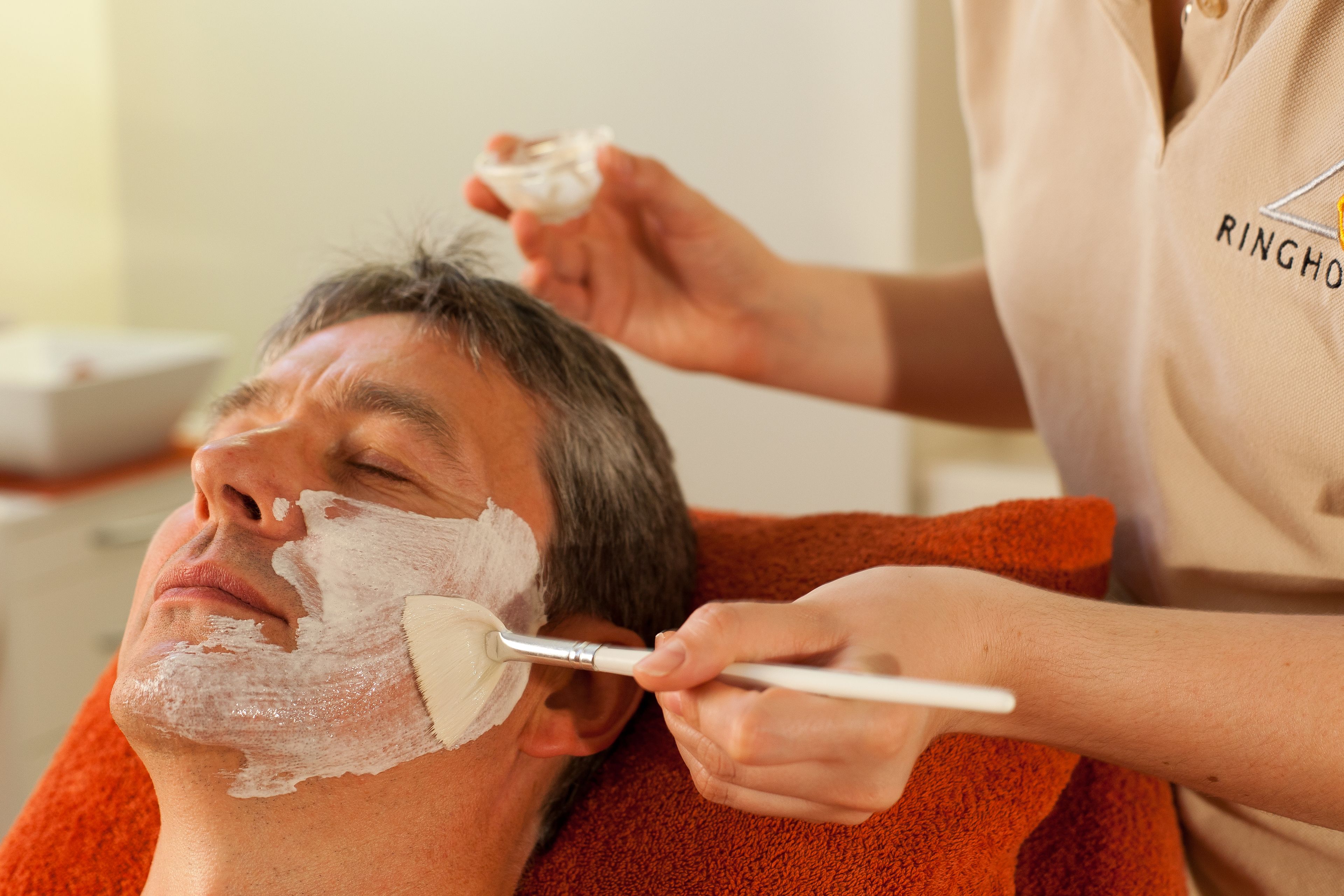 A person receiving a facial treatment with a brush.