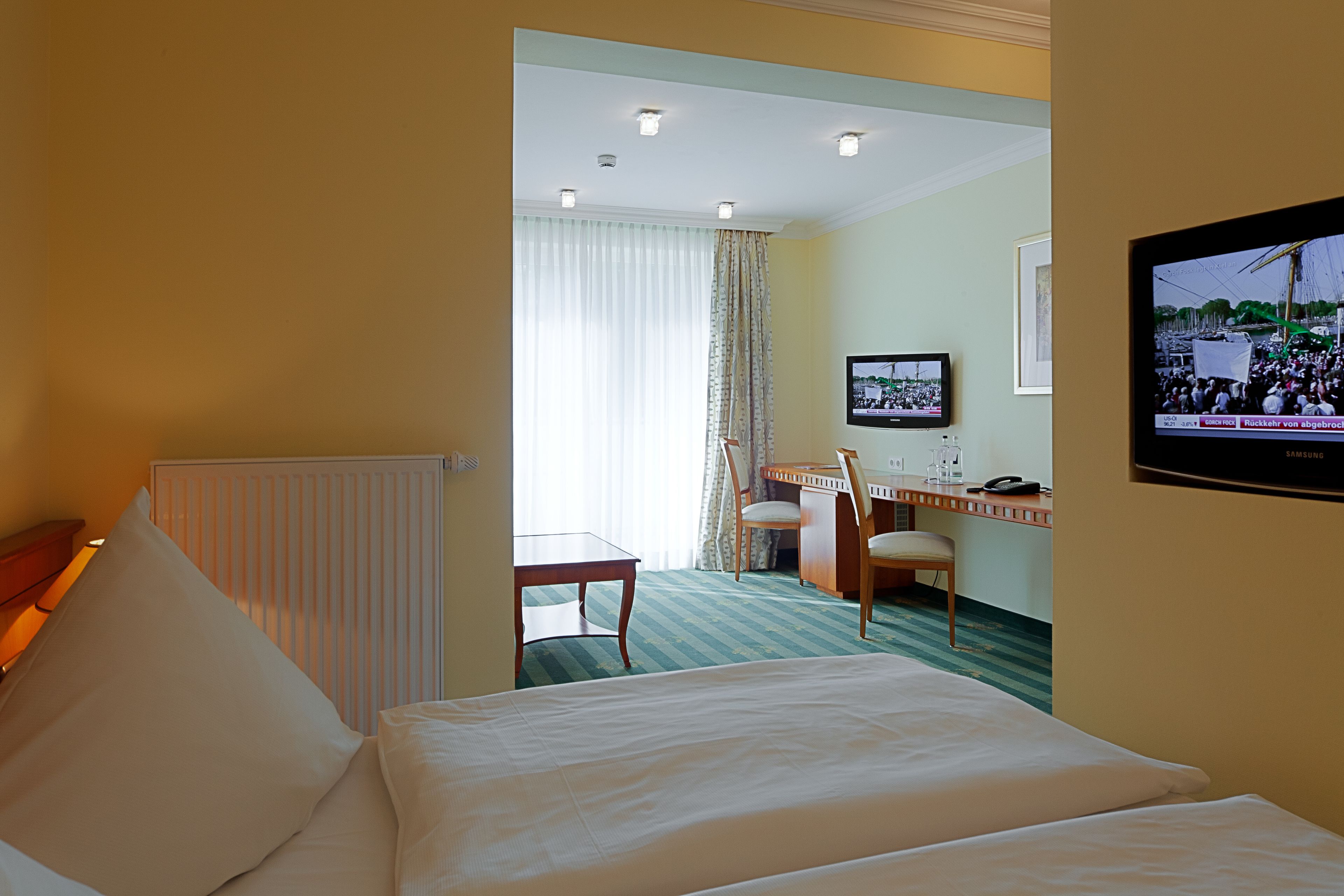 A hotel room with a bed, a desk, a chair, and a television.
