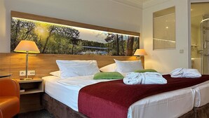 A hotel room with a bed, two bedside lamps, a nightstand, a chair, and a large window with a view of trees and a lake. - Hotel & Spa Sommerfeld - Adults Only (Kremmen)