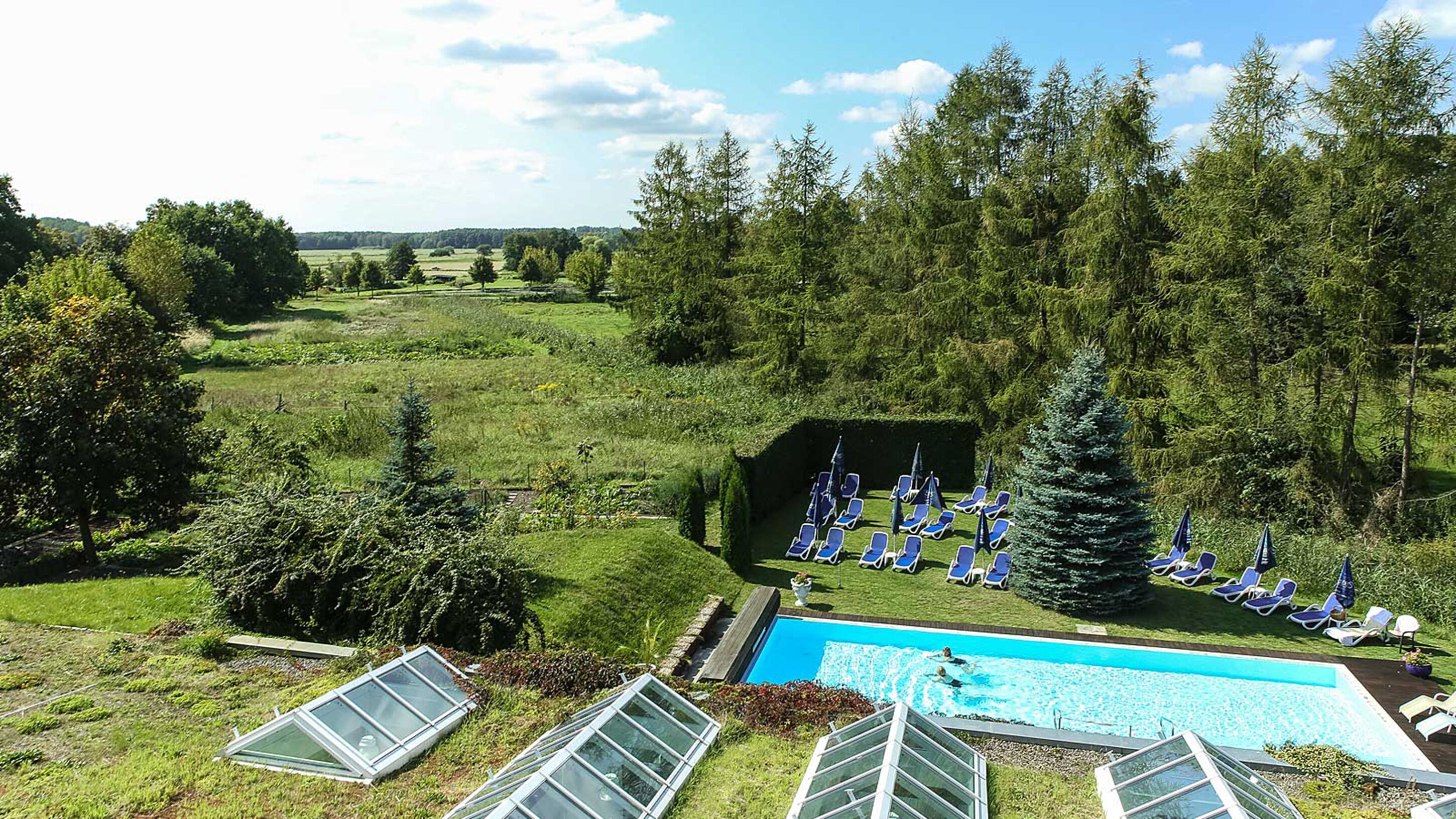 Un espace piscine doté de chaises longues et offrant une vue sur un paysage boisé.