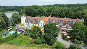 A large, multi-story hotel with a red-tiled roof, a swimming pool, and a well-maintained garden. - Hotel & Spa Sommerfeld - Adults Only (Kremmen)