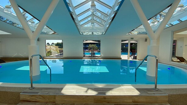 A large indoor swimming pool with clear glass ceilings and a view of the outside. - Hotel & Spa Sommerfeld - Adults Only (Kremmen)