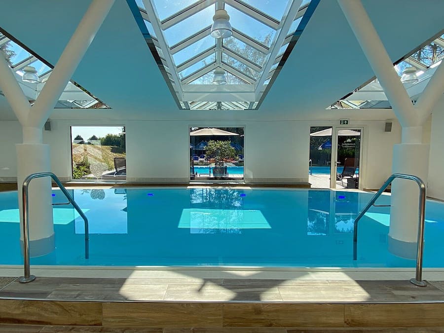 Una piscina techada, una piscina al aire libre, sombrillas