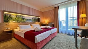 A hotel room with a large bed, a desk, a chair, a nightstand, and a wall-mounted lamp. - Hotel & Spa Sommerfeld - Adults Only (Kremmen)
