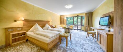 Habitación de hotel con una cama grande, un escritorio, un televisor y vistas al exterior.