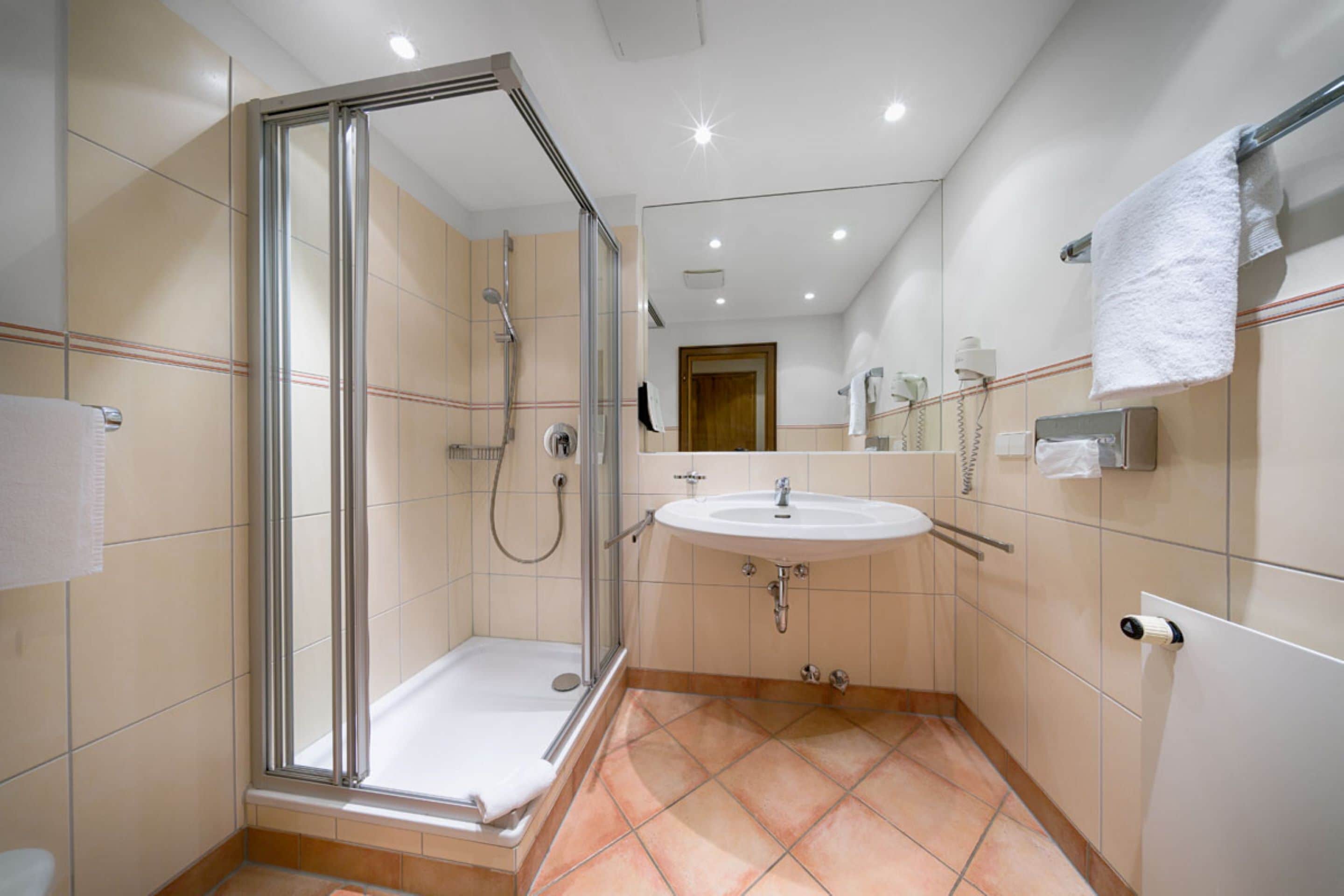 A modern bathroom with a glass-enclosed shower, a sink, and a toilet.