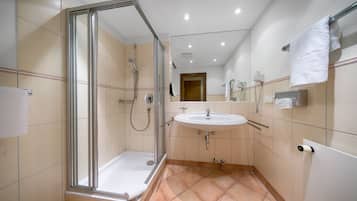 A modern bathroom with a glass-enclosed shower, a sink, and a toilet.