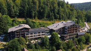 A multi-story hotel with balconies, a parking area, and a forested hillside in the background. - Ringhotel Mönchs Waldhotel (Unterreichenbach)