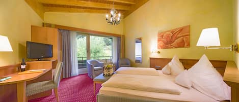 A hotel room with a wooden ceiling, a bed with white linens, a desk with a television, a chair, and a window with curtains.