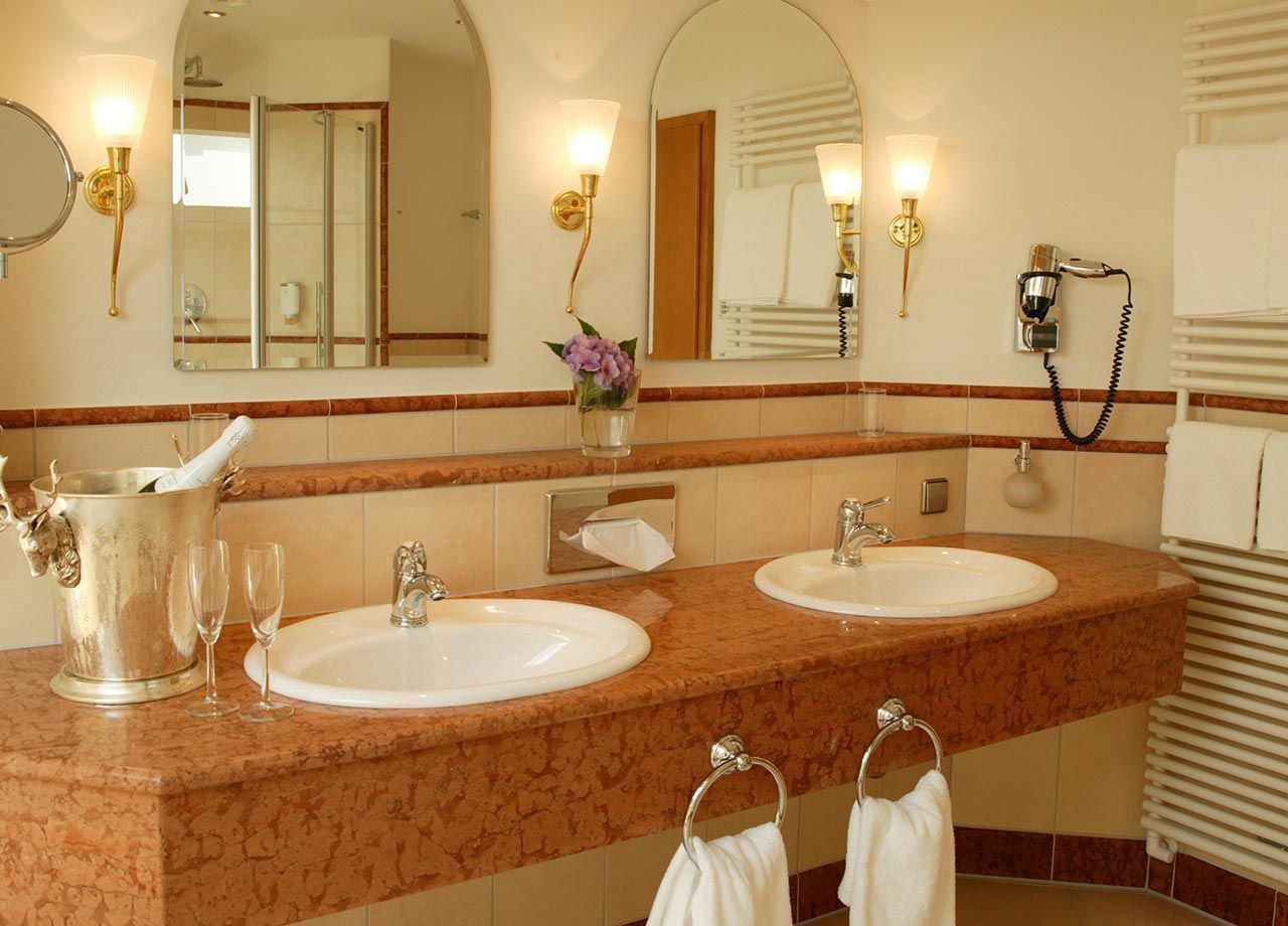A bathroom with two sinks, a large mirror, and a hairdryer mounted on the wall.