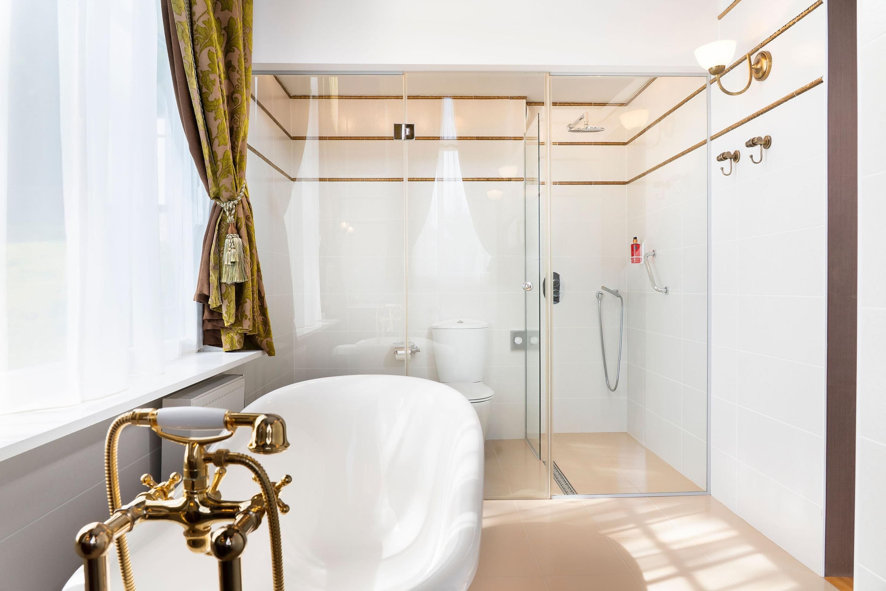 Ein modernes Badezimmer mit einer gläsernen Duschkabine, einer weißen Badewanne und einem goldenen Wasserhahn.