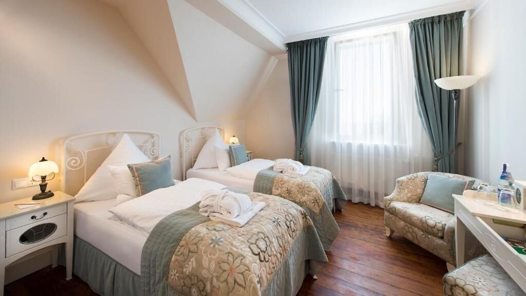 A hotel room with two beds, a desk, and a chair.
