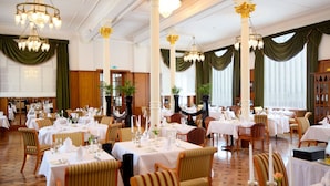 A formal dining room with multiple tables set for service, tall white columns, and chandeliers. - Das Palmenwald Schwarzwaldhof, BW Signature Collection (Freudenstadt)