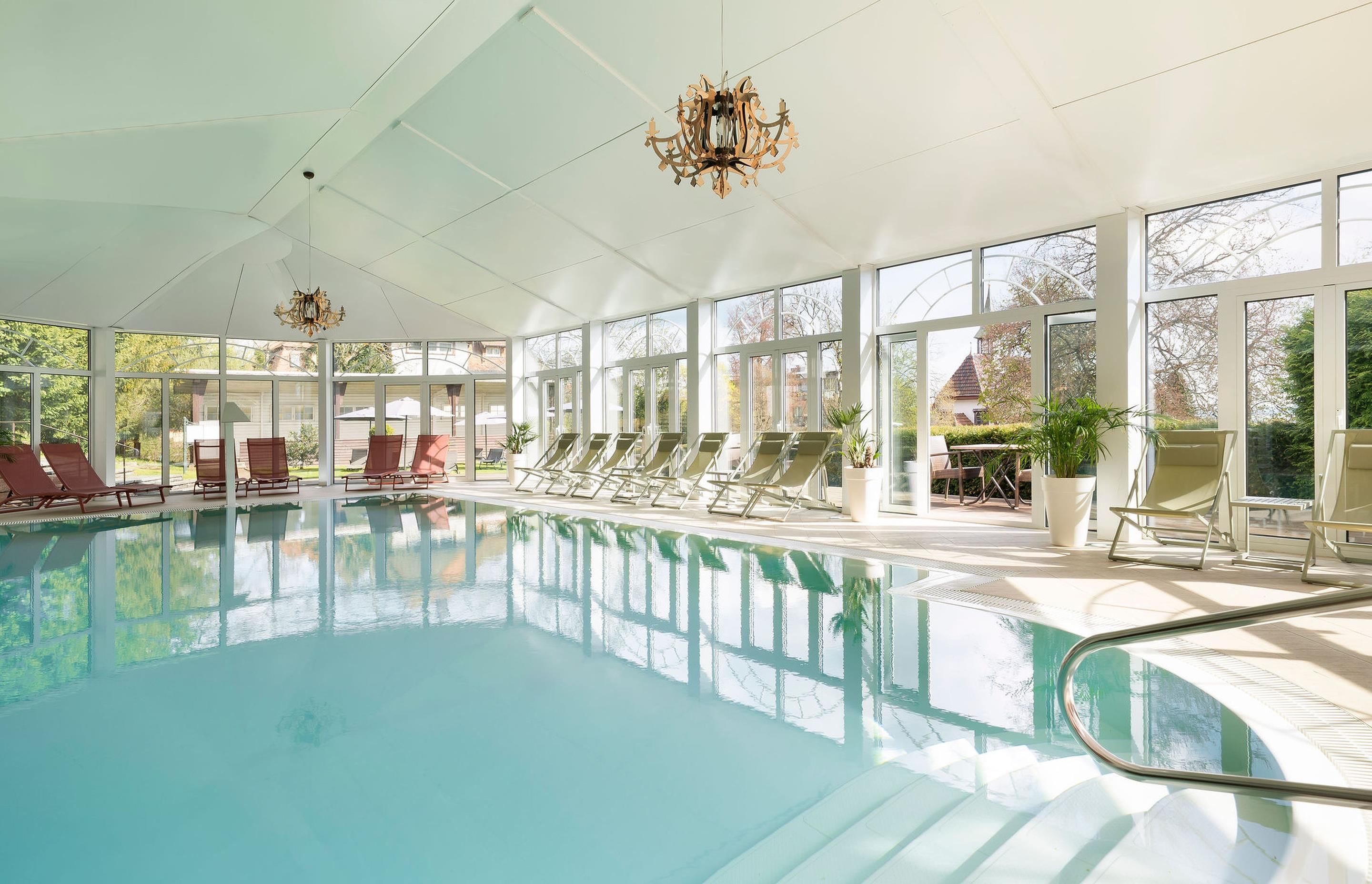 Una amplia piscina cubierta con múltiples tumbonas y un candelabro.