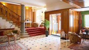 A spacious lobby with a grand staircase, comfortable seating areas, and a large potted plant. - Das Palmenwald Schwarzwaldhof, BW Signature Collection (Freudenstadt)