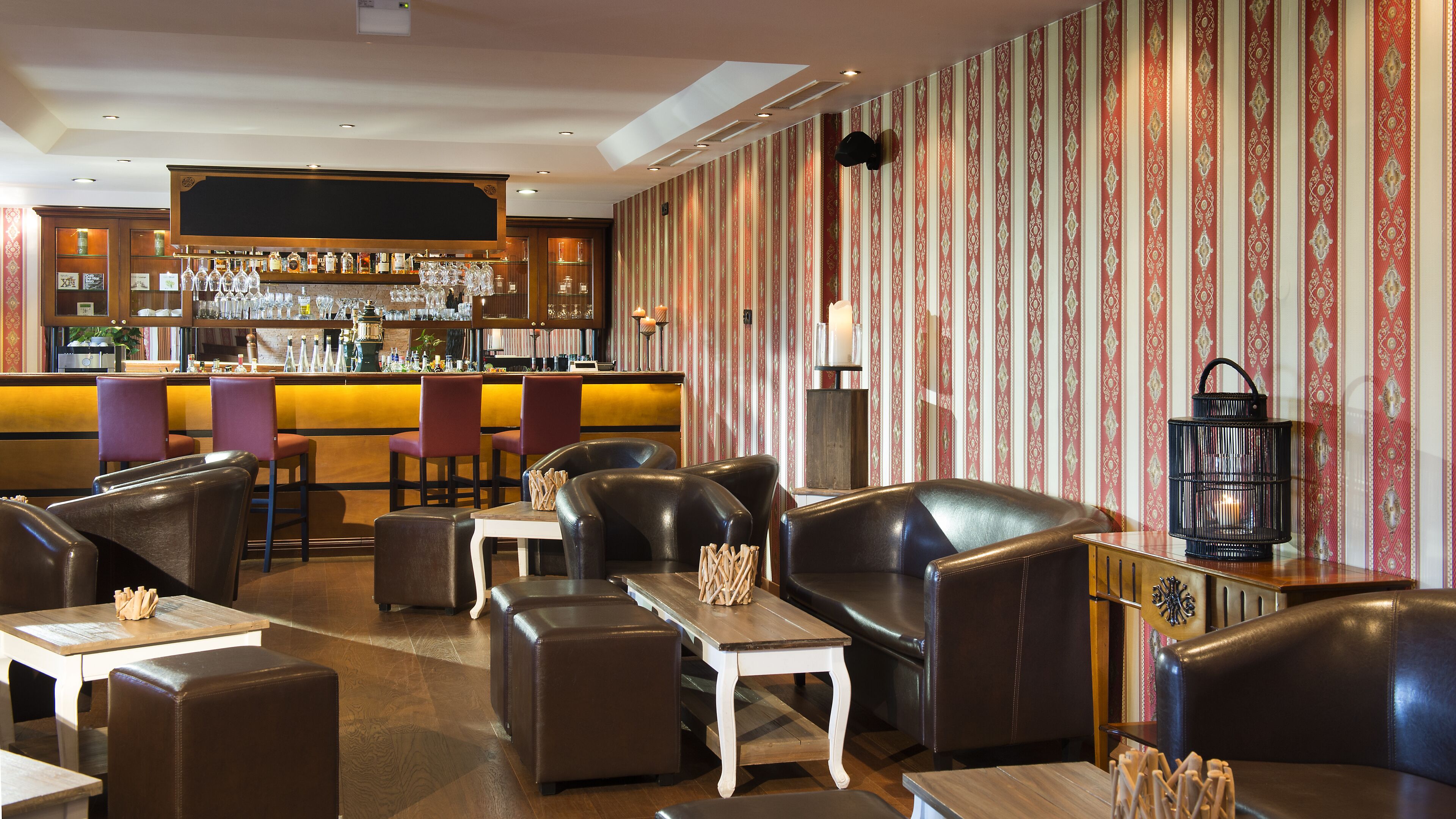A bar area with a counter, bar stools, and a seating area with leather sofas and tables.